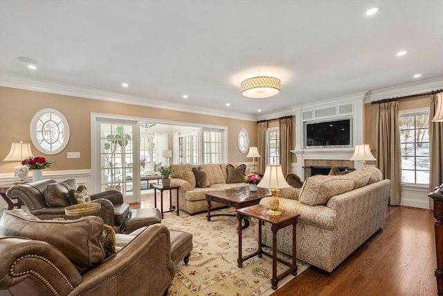 living area with a wainscoted wall, ornamental molding, wood finished floors, a fireplace, and recessed lighting