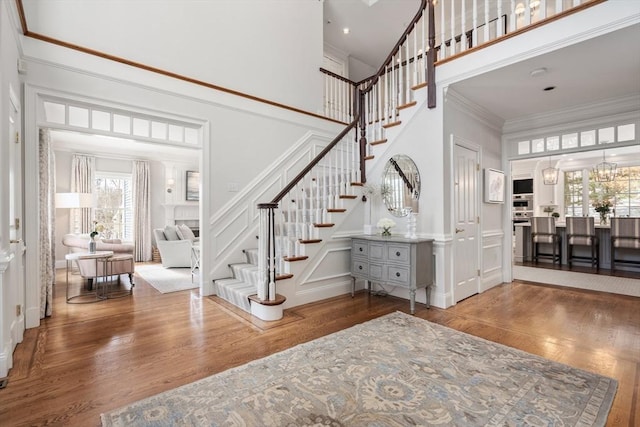 entryway featuring stairs, ornamental molding, wood finished floors, and a decorative wall