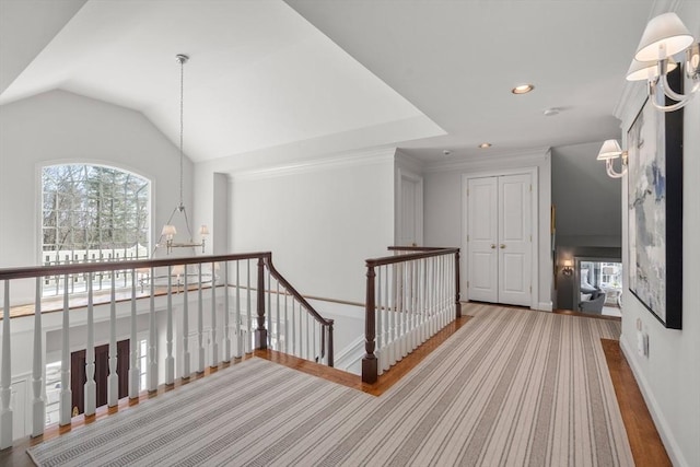 corridor featuring lofted ceiling, a healthy amount of sunlight, an upstairs landing, and an inviting chandelier