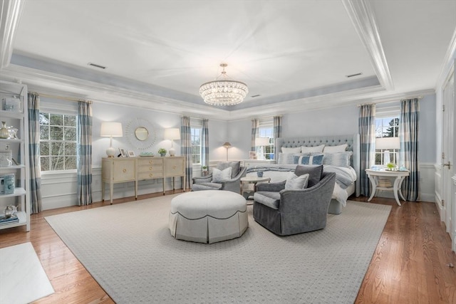 bedroom featuring wood finished floors, multiple windows, a raised ceiling, and crown molding