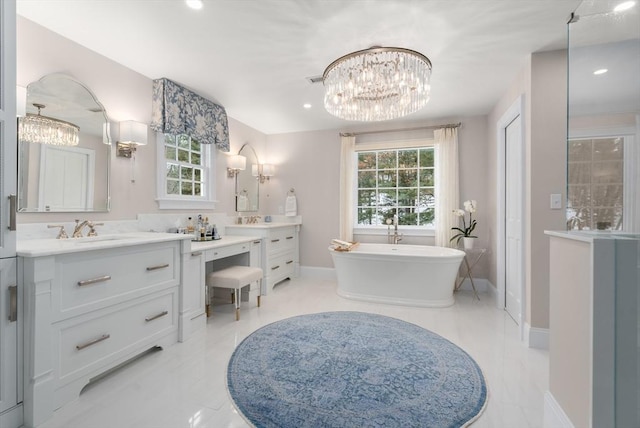 full bath with a freestanding tub, a notable chandelier, vanity, and baseboards