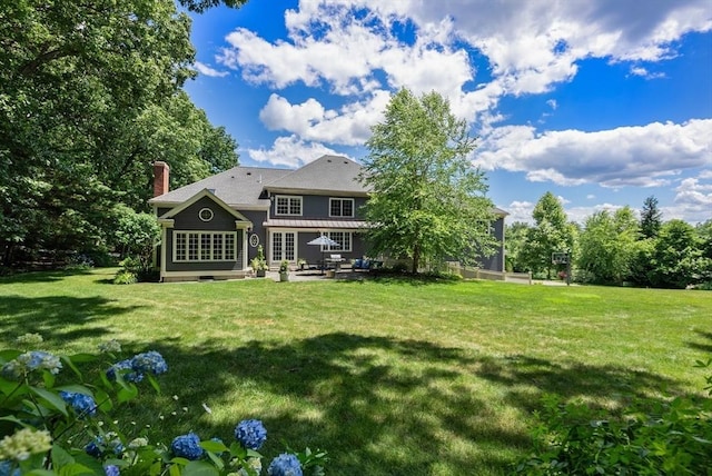 back of house with a lawn, a chimney, and a patio