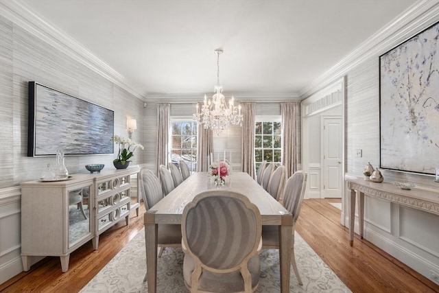 dining space with ornamental molding, light wood-style floors, and a notable chandelier