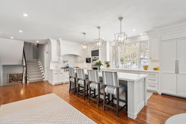 kitchen with a kitchen island, decorative light fixtures, light countertops, a kitchen bar, and white cabinetry