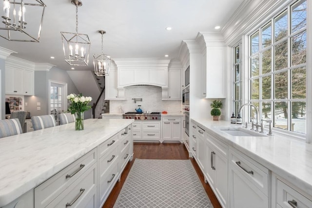 kitchen with a breakfast bar, light stone countertops, decorative light fixtures, and white cabinetry