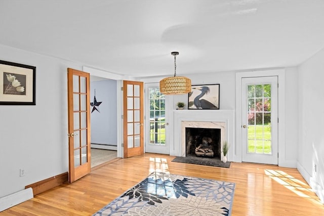 67 Greenfield Ln, Scituate, MA 02066 - living room with baseboard heating, french doors, wood finished floors, baseboards, and a fireplace
