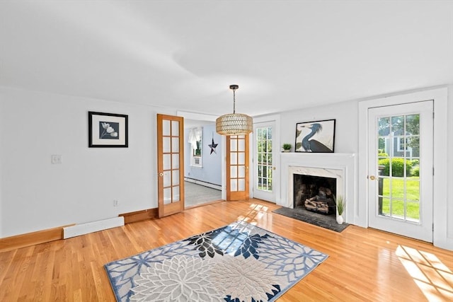 67 Greenfield Ln, Scituate, MA 02066 - unfurnished living room featuring light wood finished floors, baseboards, a baseboard heating unit, and a fireplace