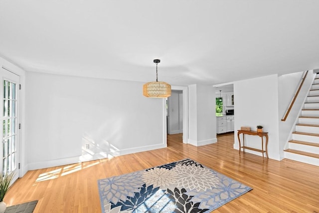 67 Greenfield Ln, Scituate, MA 02066 - unfurnished living room featuring baseboards, stairway, light wood finished floors, and a chandelier
