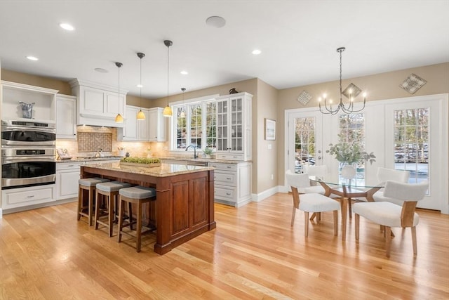 kitchen featuring a kitchen bar, appliances with stainless steel finishes, white cabinets, and backsplash