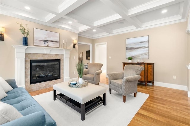 living area featuring baseboards, beamed ceiling, a brick fireplace, and light wood-style floors