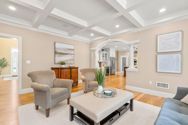 living area featuring arched walkways, beam ceiling, visible vents, light wood-style flooring, and ornate columns