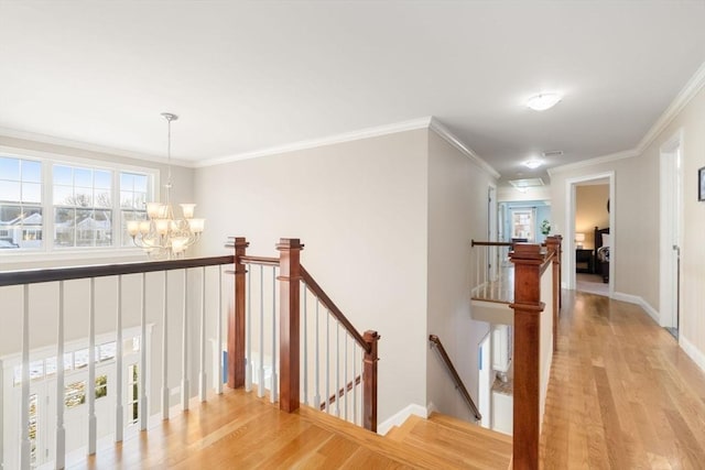 corridor featuring light wood-type flooring, a chandelier, a wealth of natural light, and an upstairs landing