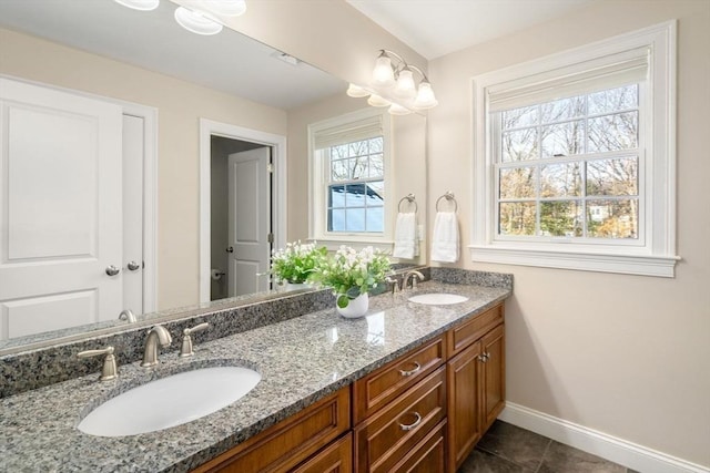 bathroom featuring tile patterned flooring, a sink, baseboards, and double vanity