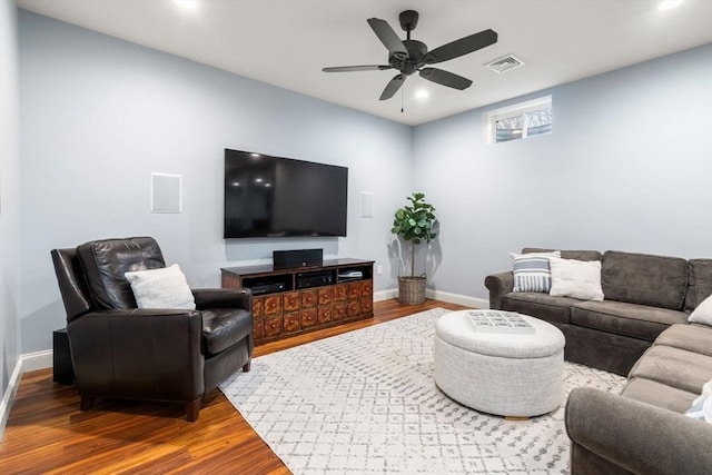 living room featuring a ceiling fan, wood finished floors, visible vents, and baseboards