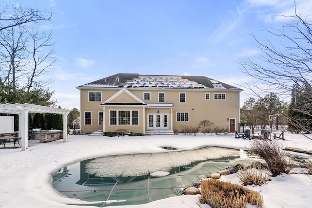 snow covered property featuring entry steps, a patio, a covered pool, french doors, and a pergola