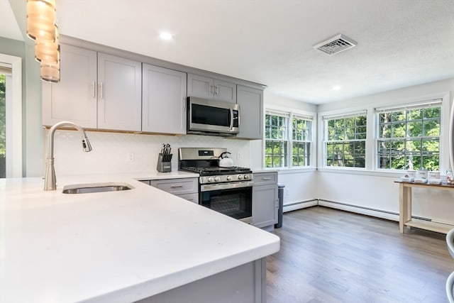 kitchen featuring a textured ceiling, dark hardwood / wood-style floors, gray cabinetry, appliances with stainless steel finishes, and sink