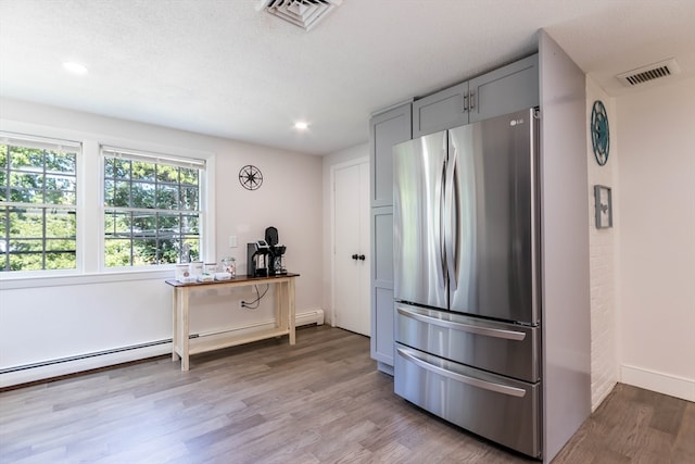 kitchen featuring light wood-type flooring, a textured ceiling, stainless steel refrigerator, and gray cabinetry