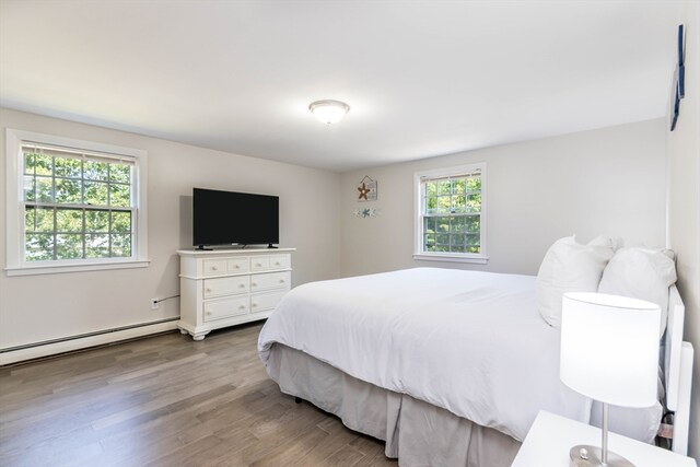 bedroom with multiple windows, a baseboard radiator, and hardwood / wood-style floors