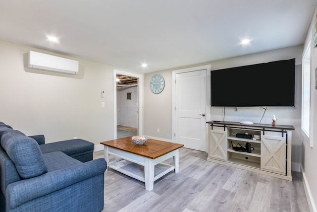 living room with a wall mounted AC and light hardwood / wood-style flooring