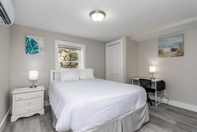 bedroom featuring a wall mounted AC, hardwood / wood-style floors, and a closet