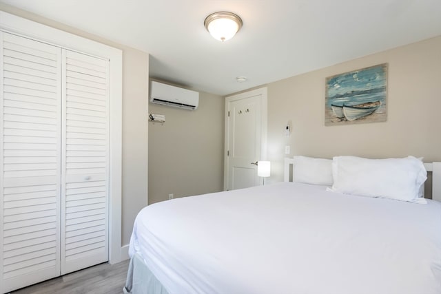 bedroom with a closet, a wall unit AC, and light hardwood / wood-style floors