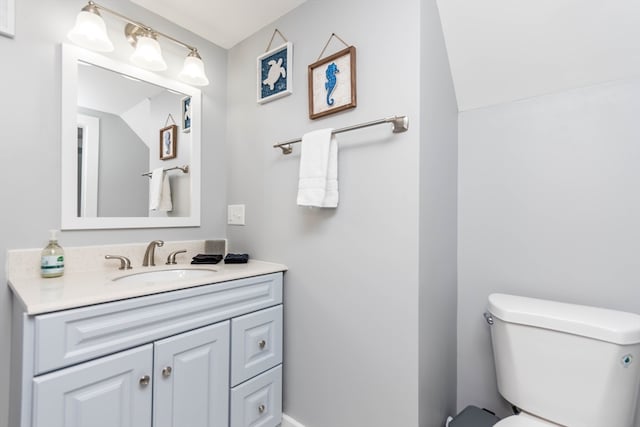 bathroom featuring lofted ceiling, toilet, and vanity