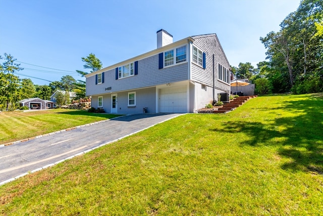 view of front of home featuring a garage, a front yard, and central AC unit