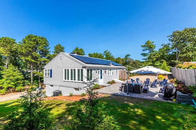 back of house with a lawn, an outdoor hangout area, solar panels, and a patio area