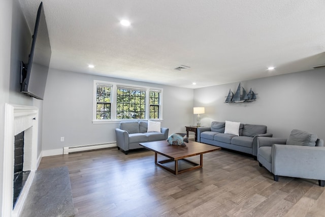 living room with a baseboard heating unit, hardwood / wood-style flooring, and a textured ceiling