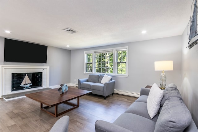 living room with a textured ceiling, hardwood / wood-style floors, and a baseboard radiator