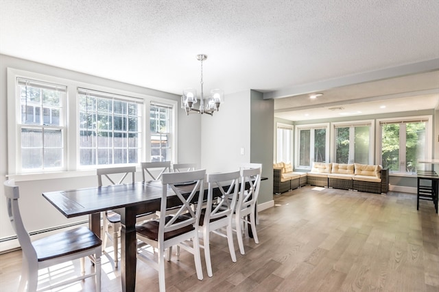 dining space with a textured ceiling, a wealth of natural light, and light hardwood / wood-style flooring