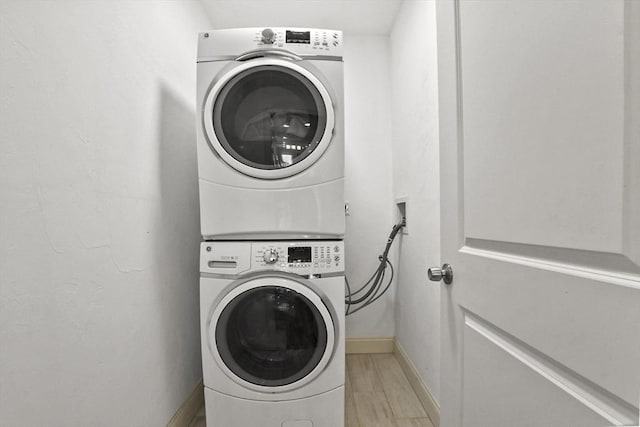 laundry room with light wood-type flooring and stacked washer and clothes dryer