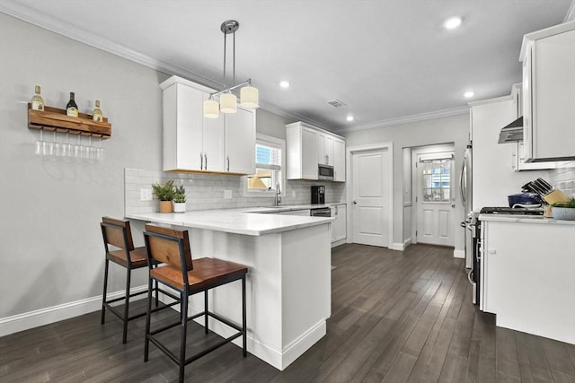 kitchen featuring a kitchen bar, backsplash, white cabinetry, decorative light fixtures, and kitchen peninsula