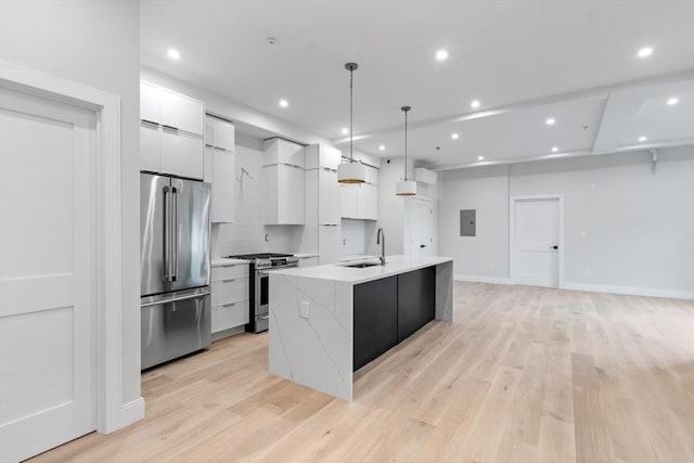 kitchen with white cabinets, an island with sink, modern cabinets, appliances with stainless steel finishes, and light wood-style floors