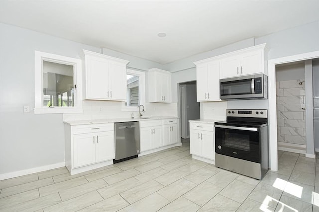 kitchen with white cabinets, appliances with stainless steel finishes, and backsplash