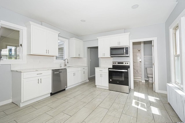 kitchen featuring backsplash, sink, white cabinetry, and stainless steel appliances