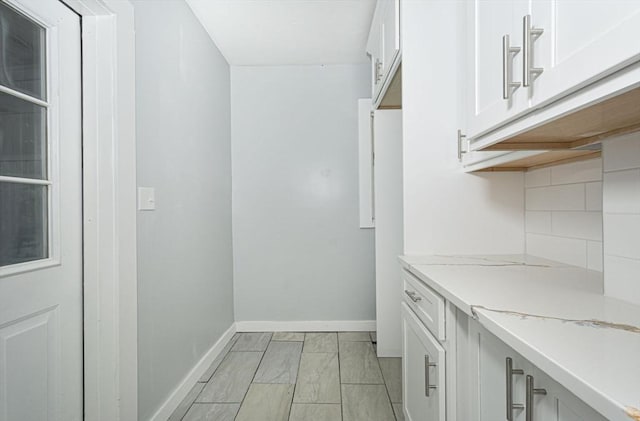 interior space featuring light stone countertops, white cabinetry, and tasteful backsplash