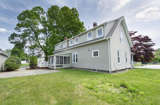 rear view of house featuring a lawn and a sunroom