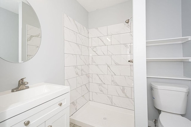 bathroom with a tile shower, vanity, and toilet