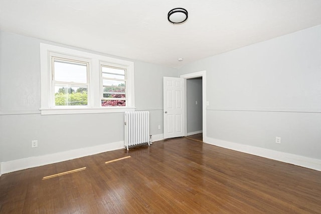 empty room featuring radiator heating unit and dark hardwood / wood-style floors