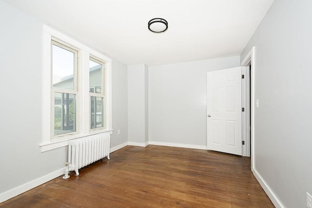 unfurnished room with radiator and dark wood-type flooring