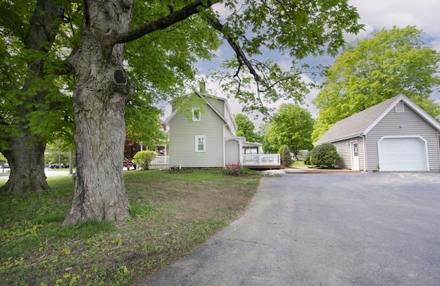 view of side of home featuring a garage, an outbuilding, and a deck