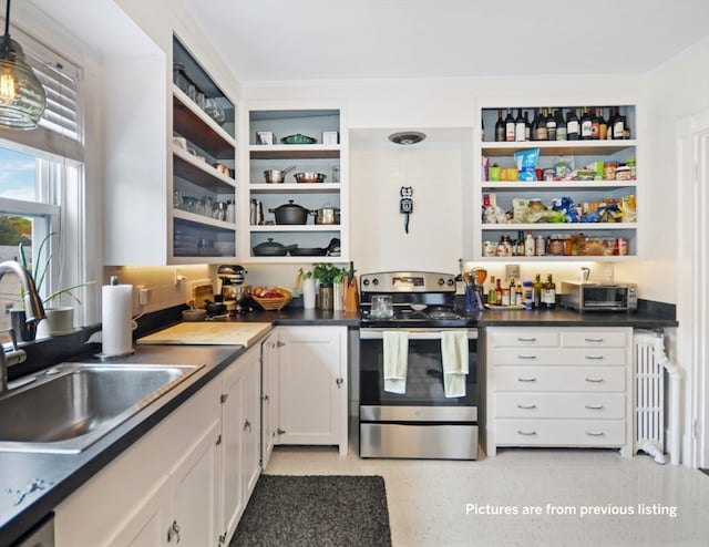 kitchen featuring stainless steel electric stove, sink, hanging light fixtures, white cabinetry, and radiator heating unit