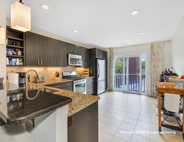 kitchen with sink, light stone countertops, light tile patterned floors, kitchen peninsula, and stainless steel appliances