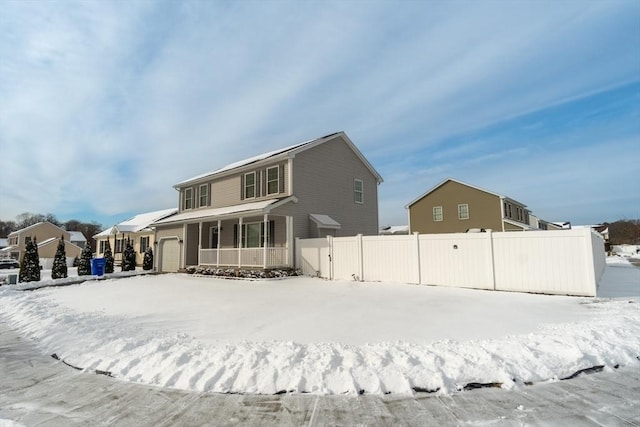 snow covered back of property with a porch