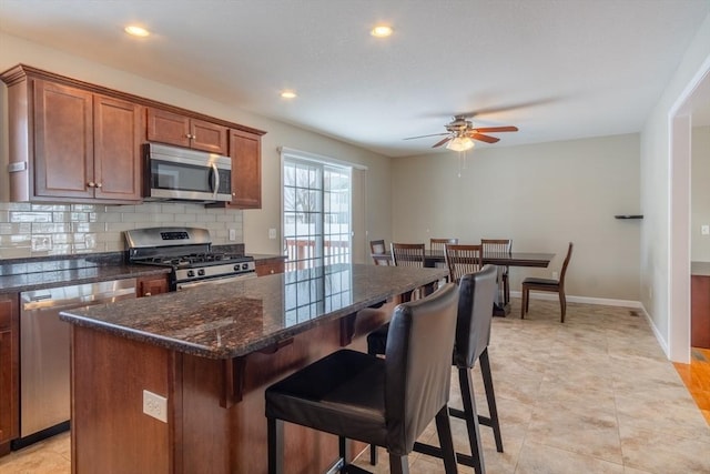 kitchen with backsplash, a breakfast bar area, stainless steel appliances, and a center island