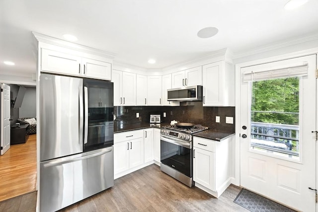 77 Marblehead St, North Reading, MA 01864 - kitchen featuring stainless steel appliances, dark countertops, wood finished floors, backsplash, and white cabinetry
