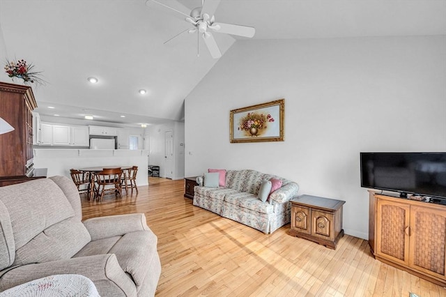 living room featuring light hardwood / wood-style flooring, high vaulted ceiling, and ceiling fan