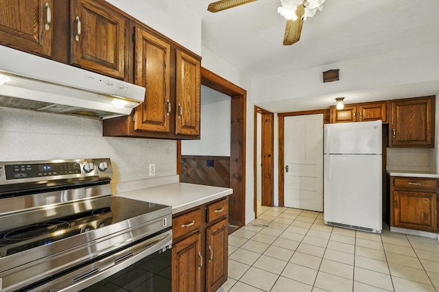 kitchen featuring white refrigerator, light tile patterned floors, stainless steel range with electric cooktop, and ceiling fan