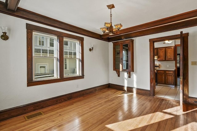 spare room with light wood-type flooring and an inviting chandelier